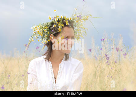 Dans un domaine luxuriant fille avec une couronne de fleurs sur la tête. Banque D'Images