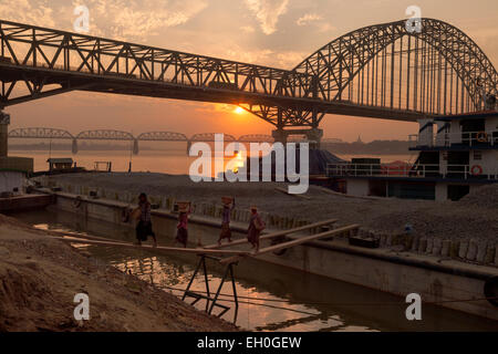 Coucher du soleil sur les ponts ferroviaires sur le fleuve Irrawaddy à Mandalay, les femmes travaillant dans l'avant-plan, le Myanmar ( Birmanie ), l'Asie Banque D'Images