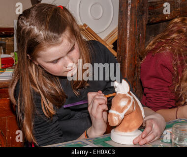 Fille (10 ans) un cheval avec la Poterie Peinture Peinture céramique à l'atelier de poterie à Banque D'Images