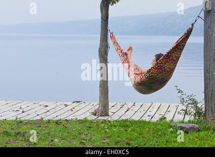 L'homme se détend en hamac par le bord du lac. Banque D'Images