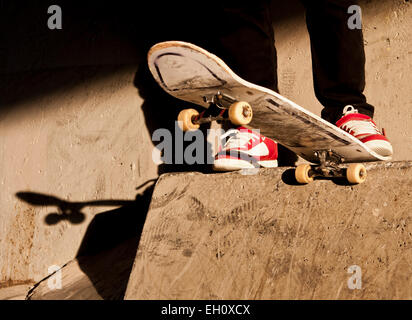 Fermer la vue d'un skateboard mans et pieds juste avant qu'il tombe sur un bloc de béton. Banque D'Images