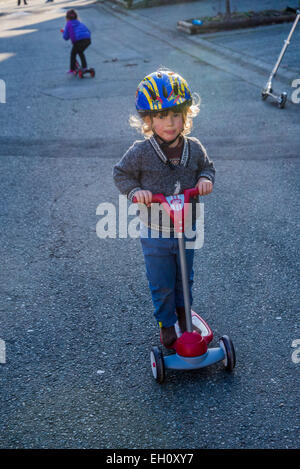 Jeune garçon de rue sur scooter jouet. Banque D'Images