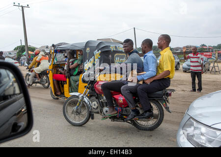 Lagos, Nigéria ; trois jeunes hommes sur une moto réussir un Tuc Tuc-taxi. Banque D'Images