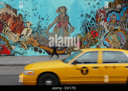 Une cabine jaune s'accélère au-delà d'une murale colorée installée par Swoon sur le mur mural Bowery mural de Houston Street, sur le côté inférieur-est Banque D'Images