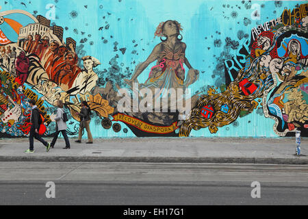 Les New Yorkers marchent pour passer devant une fresque colorée installée par Swoon sur le mur mural Bowery mural sur Houston Street dans le Bas Banque D'Images