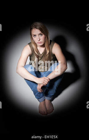Malheureux Jeune femme assise à l'extérieure de la lumière Banque D'Images