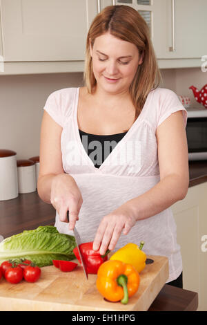 Femme enceinte jusqu'à hacher les légumes frais Banque D'Images