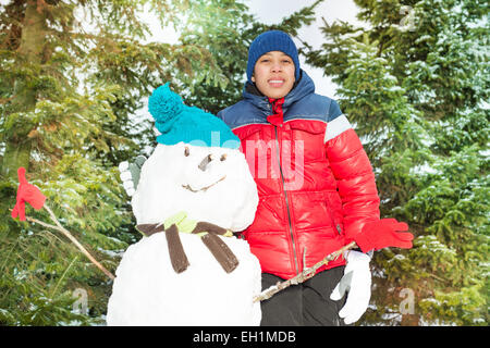 Garçon arabe debout près de bonhomme de neige en hiver Banque D'Images