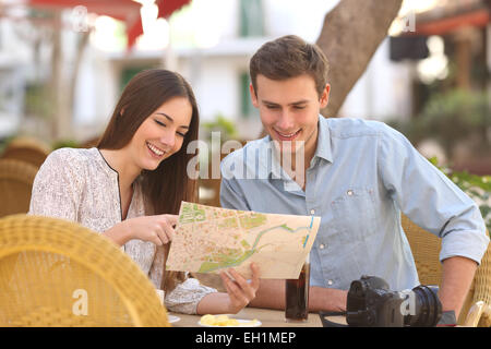 Couple heureux touristes consulting un guide dans un restaurant terrasse Banque D'Images