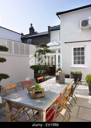 Arbre en pot, grande table et chaises en arrière-cour pavée de maison résidentielle, Burlington Road, London, England, UK Banque D'Images