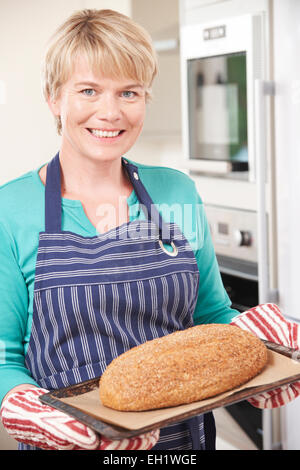 Woman in Kitchen Holding Tray With pain fait maison Banque D'Images