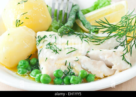 Cabillaud cuit avec du beurre fondu et de l'aneth. Servi avec Pommes de terre et les pois verts. Banque D'Images