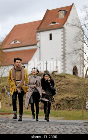 Les acteurs chinois Sun Jian (l-r), Yang Wang et Wang Xue min à pied de l'autre côté de la place du village pendant le tournage d'une scène d'une comédie romantique en chinois Hoefgen, Allemagne, 2 mars 2015. La production chinoise raconte l'histoire d'un acteur non de Beijing qui, par coïncidence, achète une maison en Allemagne. Photo : Jan Woitas/dpa Banque D'Images