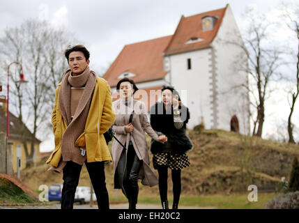 Les acteurs chinois Sun Jian (l-r), Yang Wang et Wang Xue min à pied de l'autre côté de la place du village pendant le tournage d'une scène d'une comédie romantique en chinois Hoefgen, Allemagne, 2 mars 2015. La production chinoise raconte l'histoire d'un acteur non de Beijing qui, par coïncidence, achète une maison en Allemagne. Photo : Jan Woitas/dpa Banque D'Images