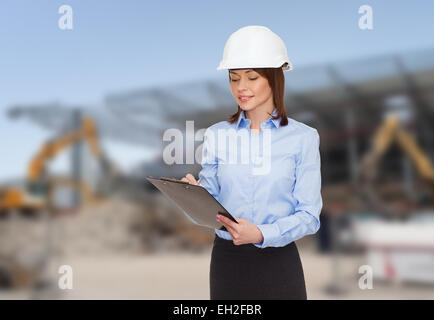 Smiling businesswoman in casque avec presse-papiers Banque D'Images