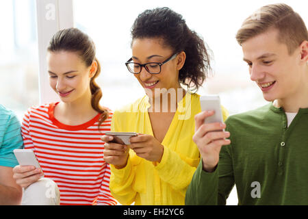 Trois étudiants souriant avec le smartphone à l'école Banque D'Images