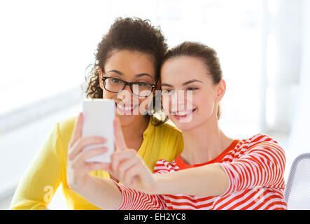 Les amies en tenant l'appareil photo de votre smartphone avec selfies Banque D'Images