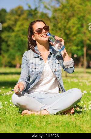 Souriante jeune fille avec une bouteille d'eau dans la région de park Banque D'Images