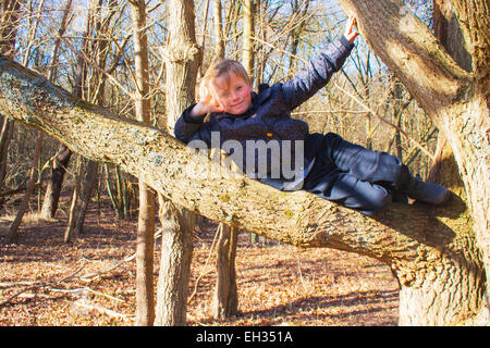 Seule fille couchée dans un arbre dans la forêt avec ciel bleu Banque D'Images