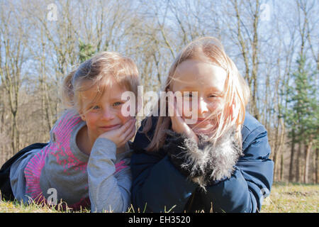 Deux petites filles, sourire à l'appareil photo dans l'herbe Banque D'Images