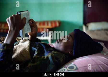 Bamenda, Cameroun, juillet 2013 ; une jeune femme, malade d'une maladie grave, la lecture de la bible dans un lit d'hôpital. Banque D'Images