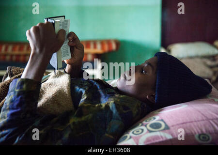 Bamenda, Cameroun, juillet 2013 ; une jeune femme, malade d'une maladie grave, la lecture de la bible dans un lit d'hôpital. Banque D'Images