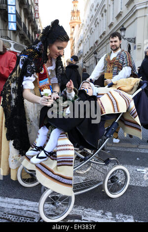 Une jeune femme en robe fallas traditionnel avec un bébé bien habillé aussi dans une poussette sur la rue Banque D'Images