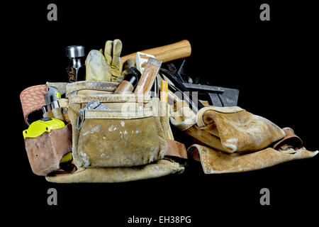 Travail du cuir robuste charpentier usés et sacs ceinture avec des outils de construction utilisé isolé sur fond noir Banque D'Images