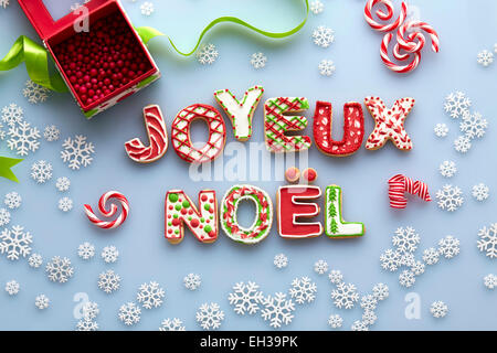 Vue de dessus de biscuits de Noël en sucre l'orthographe JOYEUX NOEL sur fond bleu avec des flocons Banque D'Images