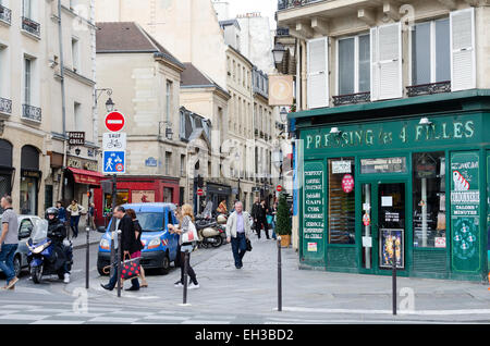 Les piétons à pied en face d'un service de blanchisserie storefront sur une étroite rue animée dans le quartier du Marais à Paris, France. Banque D'Images