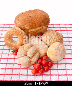 Grenier à pain et petits pains divers et des tomates cerises sur un chiffon rouge et blanc. Banque D'Images