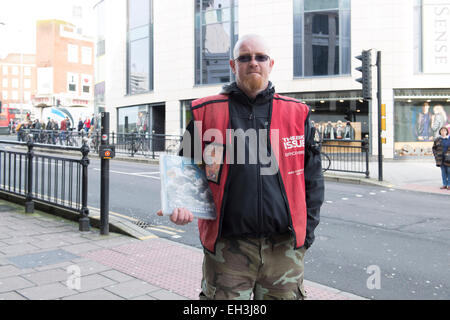 Un sans-abri se tient dans les rues de Brighton vendre la grande question Magazine pour faire une vie meilleure pour lui-même Banque D'Images