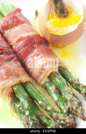 Asperges au four enveloppé de bacon, servi avec du beurre fondu et l'oeuf dur. Banque D'Images