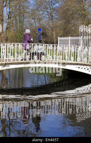 Morden Hall Park, South London, UK. 6 mars 2015. Lors d'une journée ensoleillée dans une grande partie de la France, la température a augmenté à 13 degrés dans le sud de Londres. Personnes bénéficiant d'une belle journée de printemps, avec un ciel bleu magnifique à Morden Hall Park, où la rivière Wandle passe sous le pont blanc. Credit : Julia Gavin UK/Alamy Live News Banque D'Images