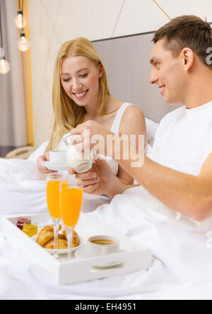 Smiling couple having breakfast in bed in hotel Banque D'Images