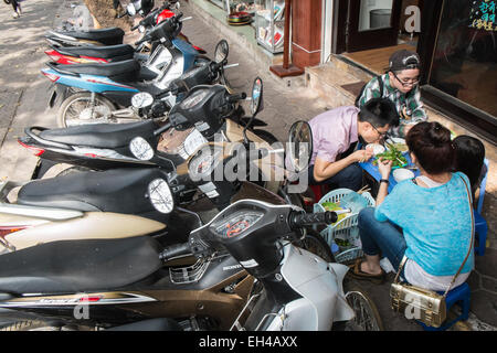 Des scooters garés sur les trottoirs et les sections locales ayant des aliments de rue,la pollution, bruit, circulation, Ha Noi, Hanoi, Vietnam, Banque D'Images