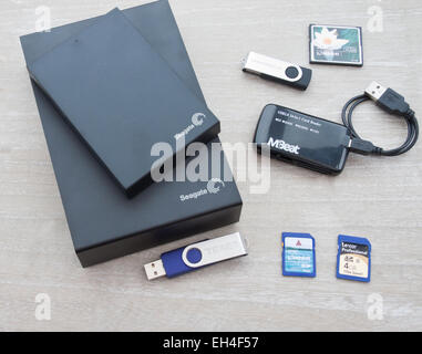 Collection de périphériques de stockage numérique, avec un lecteur de carte sur un fond de bois gris. Banque D'Images