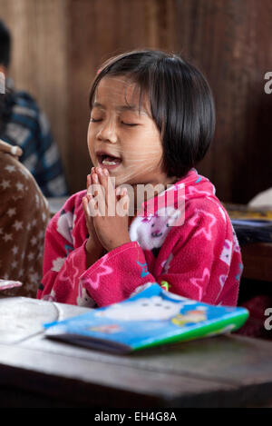 Jeune fille birmane priant dans son école de classe, Kay Lar Village l'école primaire, au Lac Inle, Myanmar ( Birmanie ), l'Asie Banque D'Images