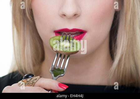 Blonde woman eating kiwi avec une fourchette Banque D'Images