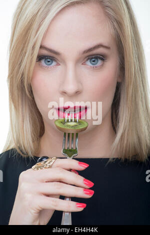 Blonde woman eating kiwi Banque D'Images