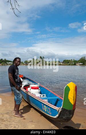 République du Suriname, Lawa River En aval du fleuve Maroni en pirogue, en charge et échouée sur le côté rive Suriname, portrait d'un passeur (Seke), dans l'arrière-plan le village de Grand-Santi Banque D'Images