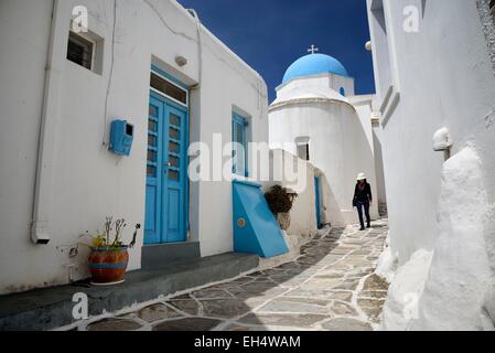 Grèce, les Cyclades, l'île de Paros, femme marche dans une rue étroite dans le village de Lefkes, petite église avec un domeEmirats bleu Arabes Unis Banque D'Images