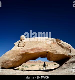 La Jordanie, Wadi Rum, zone protégée inscrite au Patrimoine Mondial de l'UNESCO, silhouette d'une femme à l'ombre d'un rocher naturel arch Banque D'Images