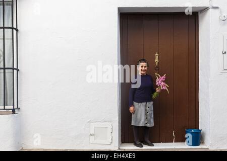 Espagne, Andalousie, Cadix, Grazalema, vieille dame à sa porte, portant un bouquet de fleurs à la main Banque D'Images