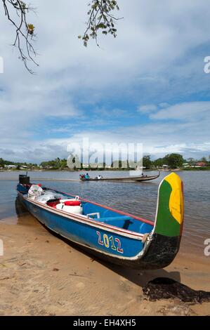 République du Suriname, Lawa River En aval du fleuve Maroni en pirogue, en charge et échoués sur la rive côté surinamais et pirogue naviguant sur le fleuve, dans l'arrière-plan le village de Grand-Santi Banque D'Images