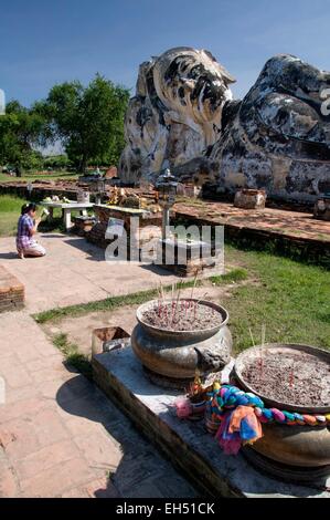 La Thaïlande, Ayutthaya, inscrite au Patrimoine Mondial de l'UNESCO, Wat Lokaya Sutha, femme en prière et de faire une offrande d'une grande statue en pierre du Bouddha couché Banque D'Images