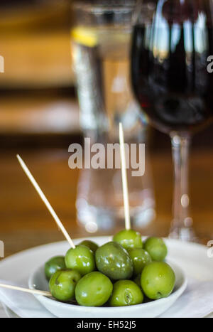 Olives vertes avec du vin rouge et de l'eau Banque D'Images