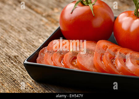 Tranches de tomates fraîches toute ​​And placés dans une plaque en céramique noire Banque D'Images