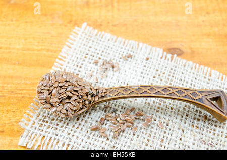 Les graines de lin dans une cuillère en bois vintage sur une nappe Banque D'Images