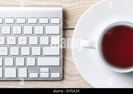 Libre d'un clavier d'ordinateur et une tasse de café chaud sur une table rustique blanc. High angle tourné en format horizontal. Banque D'Images